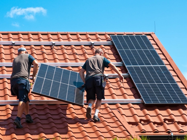 Workers install solar panels on a rooftop